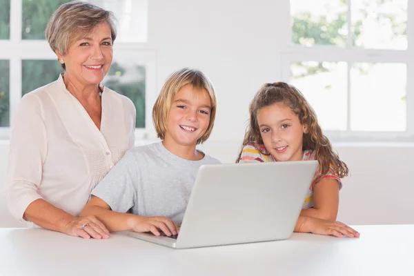 Grandmother and children looking at the camera together with lap — Stock Photo, Image