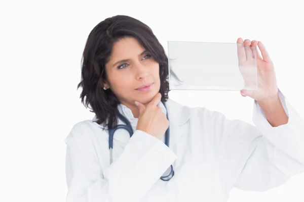 Doctor holding up virtual screen and touching the chin — Stock Photo, Image