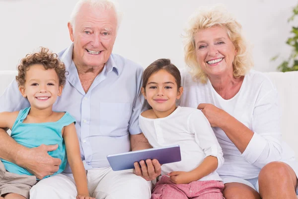 Avós sorridentes com filhos usando um tablet pc — Fotografia de Stock