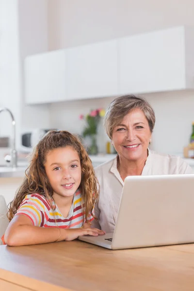 Sorrindo criança e vovó olhando para a câmera com laptop — Fotografia de Stock