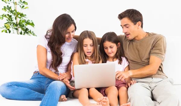 Família posando em um sofá com o computador portátil — Fotografia de Stock