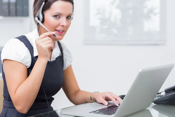 Female executive wearing headset while using laptop at desk Royalty Free Stock Images