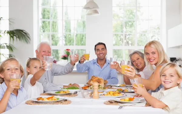 Glückliche Familie stößt beim Erntedankessen an — Stockfoto