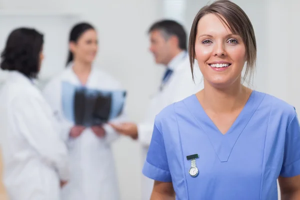 Krankenschwester lächelt mit ihrem Team im Rücken lizenzfreie Stockfotos