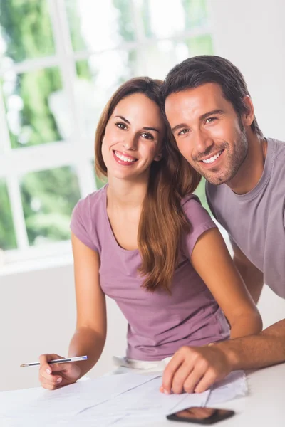 Couple smiling at the camera with invoices Stock Picture