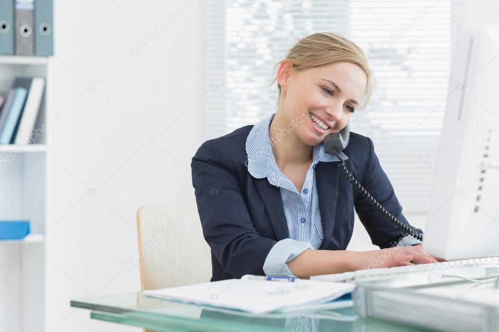 Female executive using landline phone and computer at desk Stock Photo by ©Wavebreakmedia 24110469