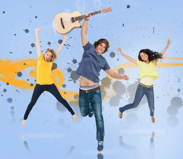 Giovane uomo con chitarra e due ragazze che saltano per la gioia — Foto Stock