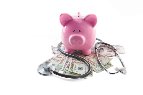 Piggy bank and stethoscope resting on pile of dollars — Stock Photo, Image