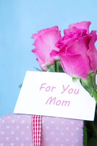 Bouquet of pink roses in vase with pink gift and mothers day car — Stock Photo, Image