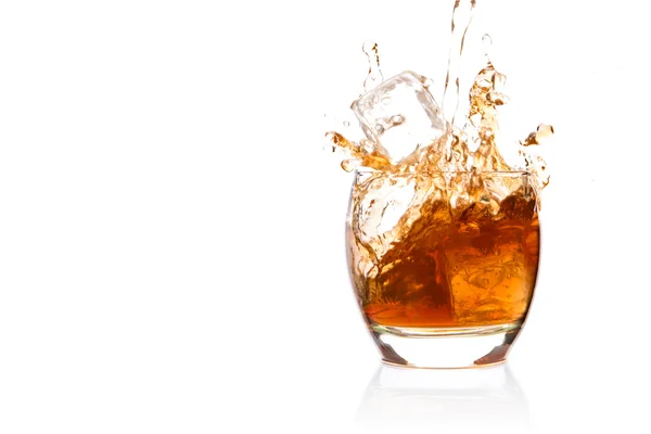 Cubo di ghiaccio che cade nel bicchiere di whisky — Foto Stock