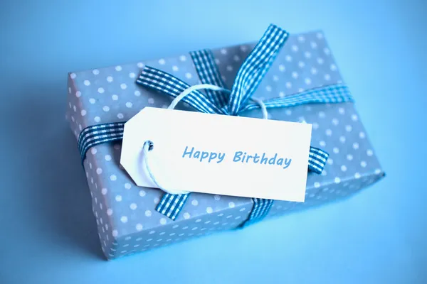 Pretty blue gift with a happy birthday card on a blue background — Stock Photo, Image