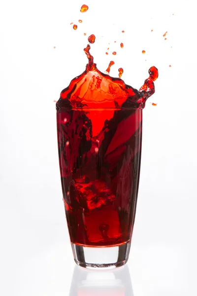 Cubes de glace tombant dans un verre de liquide rouge — Photo