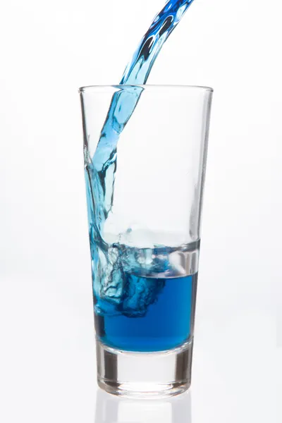 Glass being filled with blue liquid — Stock Photo, Image