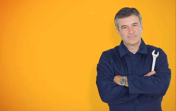 Mature mechanic standing in front of yellow background — Stok fotoğraf