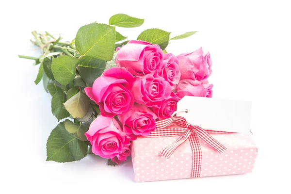Bukett med rosa rosor bredvid en gåva med ett tomt kort — Stockfoto