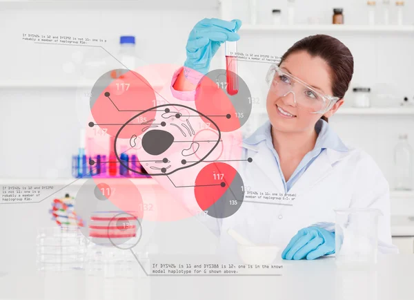 Químico sorridente olhando para tubo de ensaio de produto químico vermelho — Fotografia de Stock