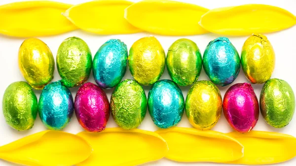 Huevos de Pascua envueltos en papel de colores con pétalos de tulipán —  Fotos de Stock