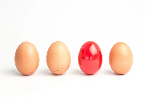 Čtyři vejce v řádku s jeden červený — Stock fotografie