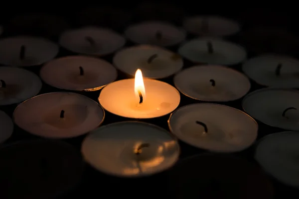 Single candle lighting surrounded by others — Stock Photo, Image