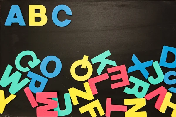Imanes del alfabeto en un revoltijo en pizarra con Abc en orden — Foto de Stock