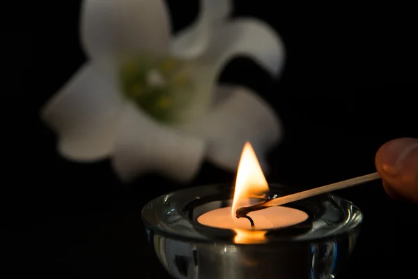 Vela de luz de té de iluminación manual con lirio blanco en el fondo — Foto de Stock