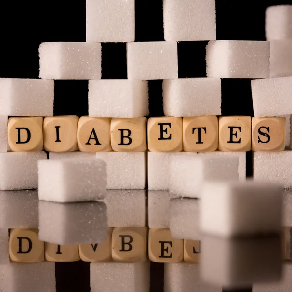 Close up on sugar cubes and dice spelling diabetes — Stock Photo, Image