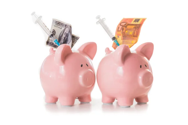 Dollar en euro notities en spuiten steken uit piggy banks — Stockfoto