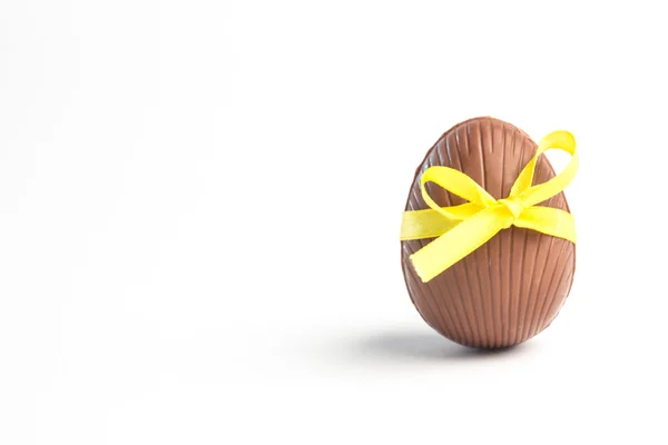 Chocolate easter egg in a yellow ribbon — Stock Photo, Image