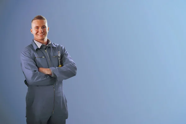 Mechanic standing in front of a blue background — Stock Photo, Image