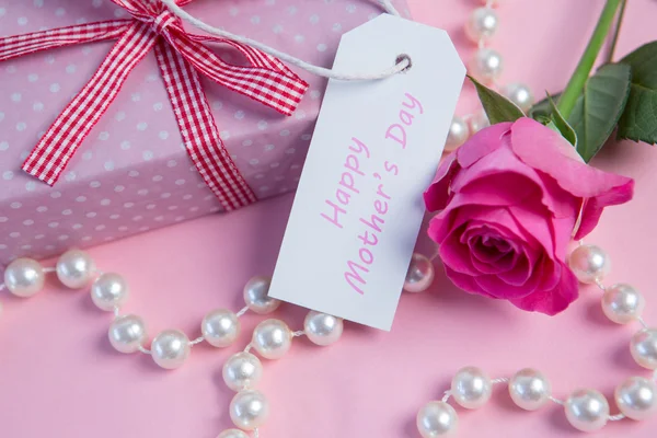 Rosa rosa con regalo y cadena de perlas y etiqueta para el día de las madres —  Fotos de Stock