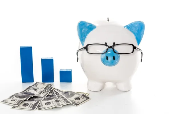 Piggy bank wearing glasses with dollars and blue graph model — Stock Photo, Image
