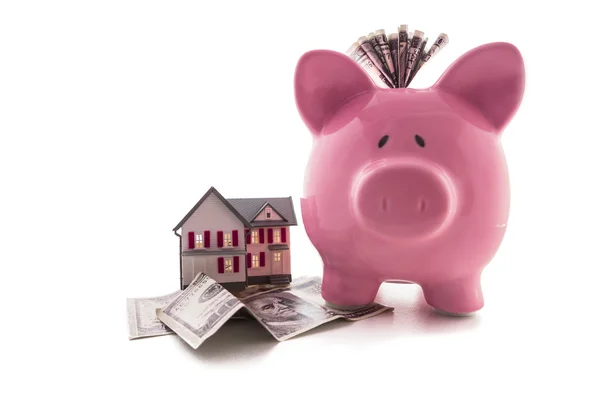 Piggy bank with dollars beside miniature house model — Stock Photo, Image