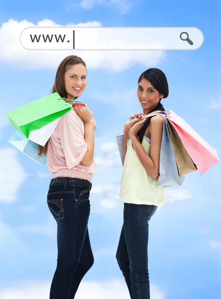 Chicas felices con sus bolsas de compras bajo la barra de direcciones —  Fotos de Stock