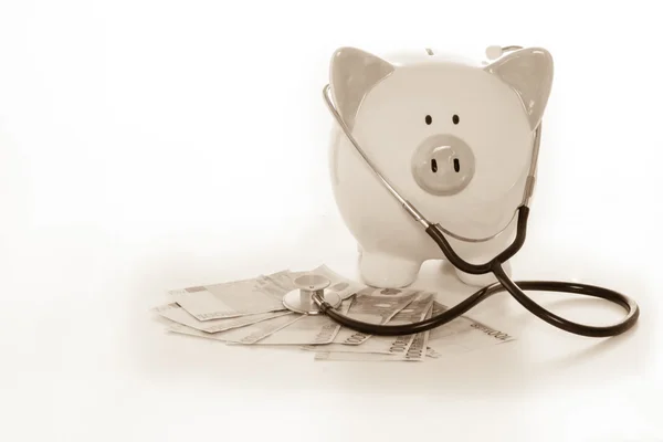 Piggy bank siedzi na stos dolarów z stetoskop — Zdjęcie stockowe