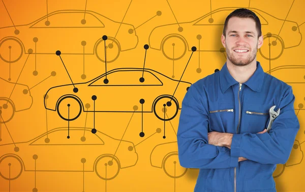 Young smiling mechanic standing in front of cars background — Stock Photo, Image