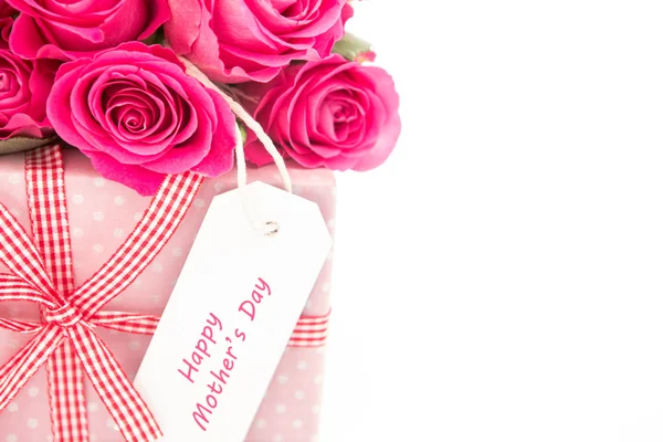 Nahaufnahme eines Straußes rosa Rosen neben einem rosa Geschenk mit einem h — Stockfoto