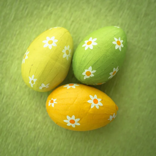 Trois oeufs de Pâques enveloppés de papier d'aluminium sur la surface verte — Photo