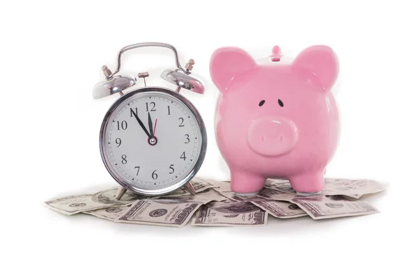 Piggy bank beside alarm clock on dollars — Stock Photo, Image