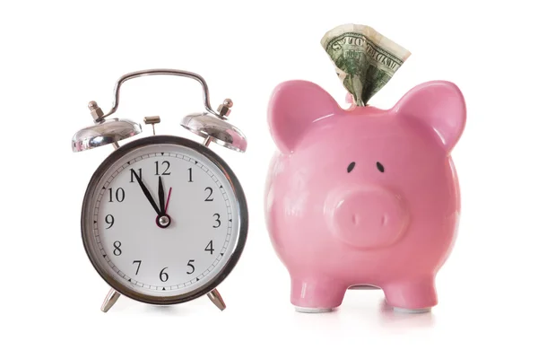 Dollar note sticking out of piggy bank beside alarm clock — Stock Photo, Image