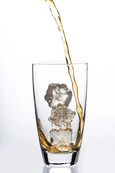 Liquide versé dans du verre avec des glaçons — Photo