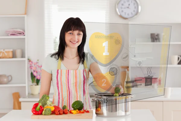 Улыбающаяся женщина готовит ужин с помощью интерфейса голограммы — стоковое фото