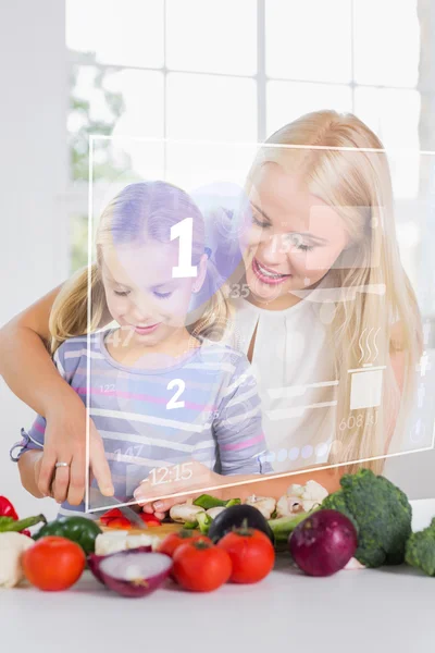 Mother and daughter chopping vegetables with holographic interfa — Stock Photo, Image