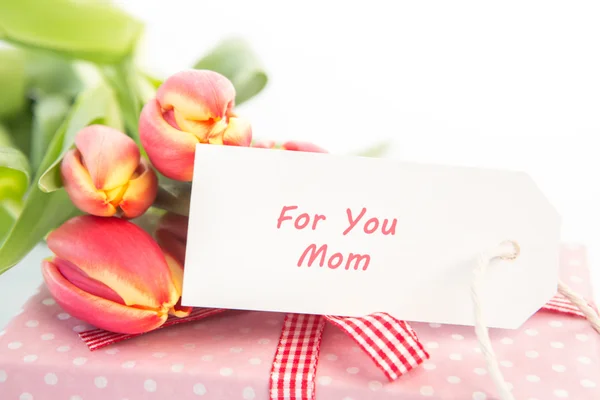 Buquê de tulipas ao lado de um presente com um cartão para uma mãe — Fotografia de Stock