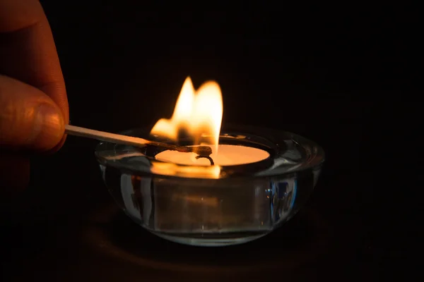 Hand lighting tea light candle in the dark — Stock Photo, Image