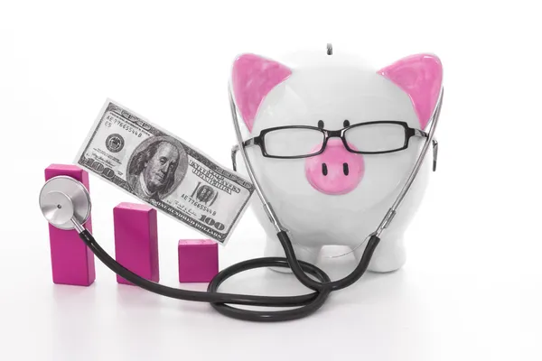 Pink and white piggy bank wearing glasses and stethoscope — Stock Photo, Image