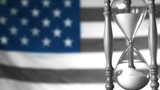 Sand flowing through hourglass with american flag in selective black and white — Wideo stockowe