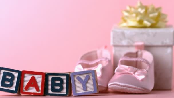 Baby blocks toppling over in front of booties and gift box — Stock Video