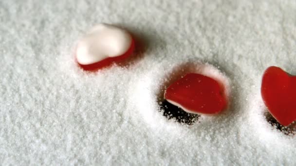 Heart shaped candies falling in pile of sugar — Stock Video