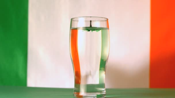 Irish flag mirrored through pint of water with green drop falling in in slow motion — Stock Video