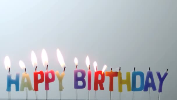 Colourful happy birthday candles being blown out — Stock Video